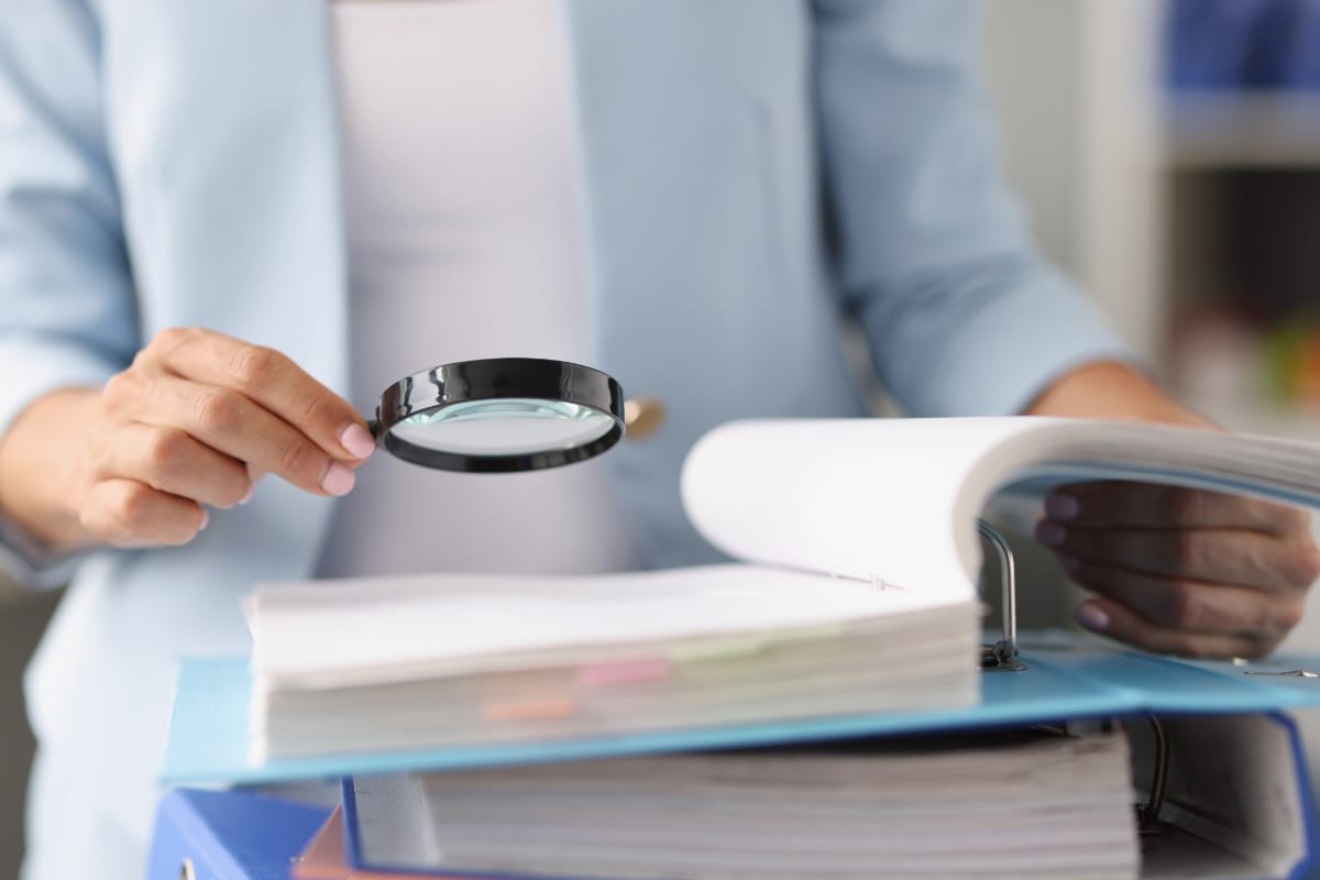 Woman holding magnifying glass over a book