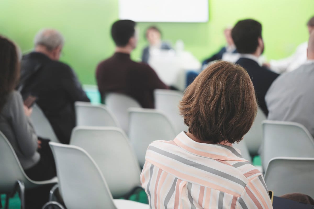AdobeStock_1866575814 Woman Sitting in Chair at a HOA Meeting